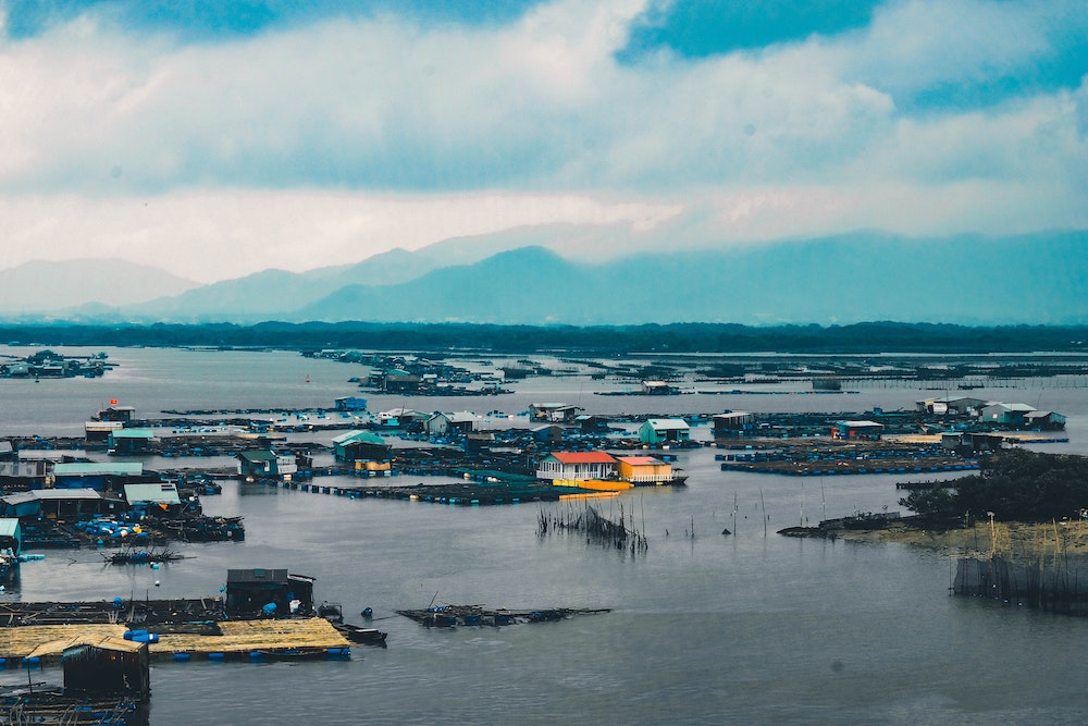 A fooded village with mountains in the background across the water.